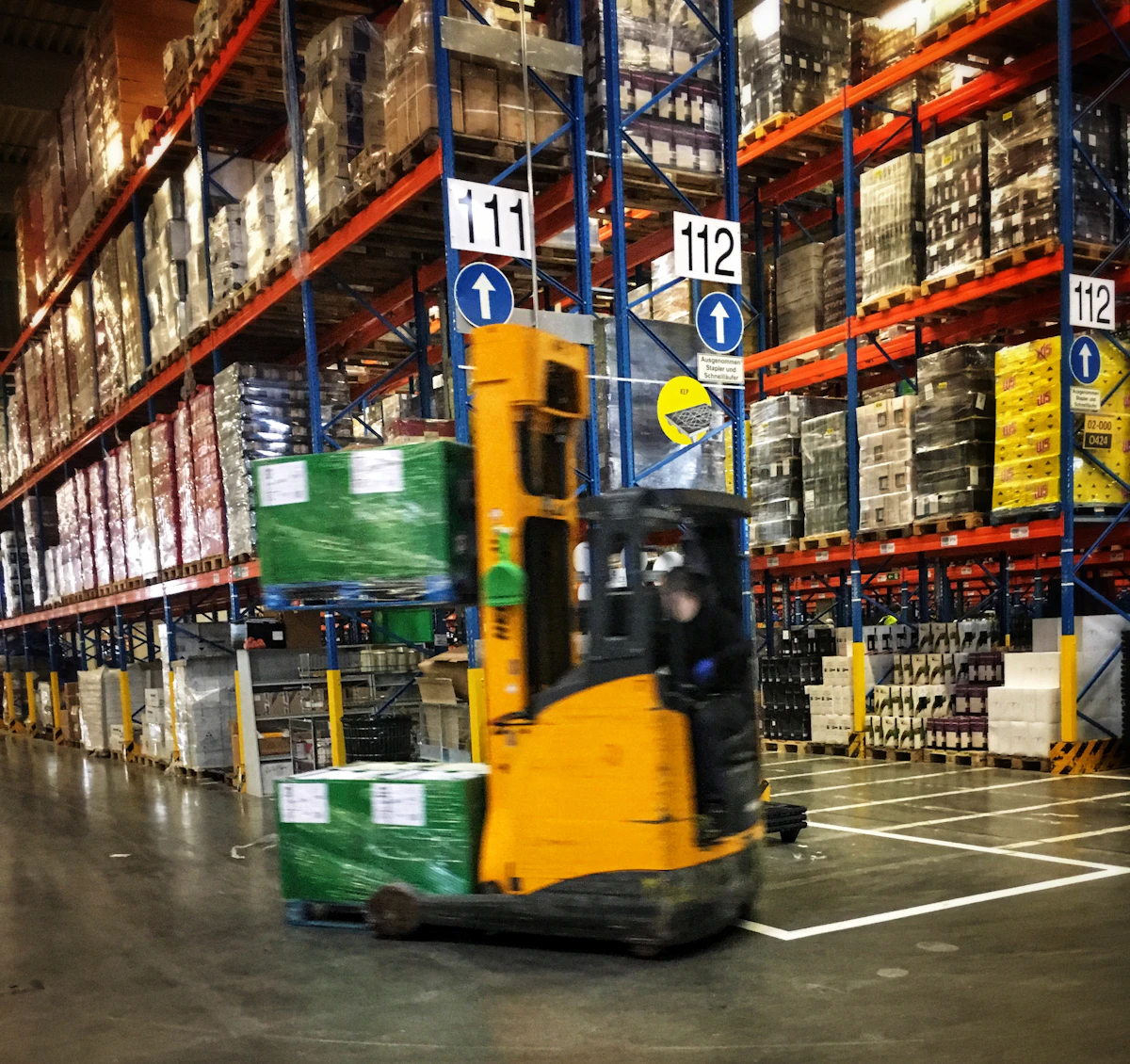 A forklift moving palletised goods through a warehouse aisle